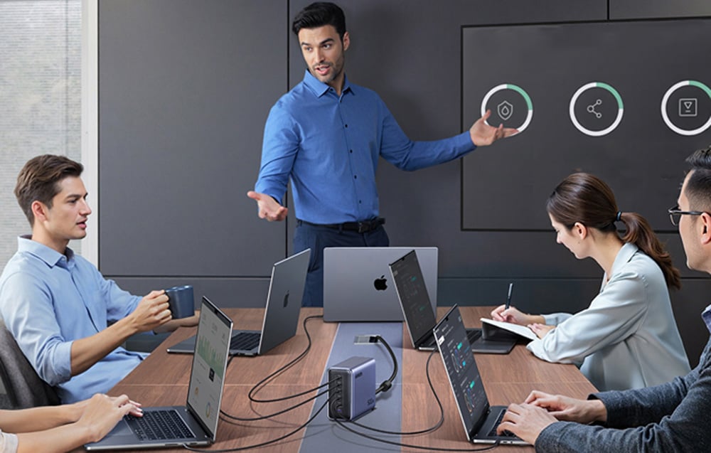 Business meeting, participants at the table with laptops connected to the UGREEN charger.