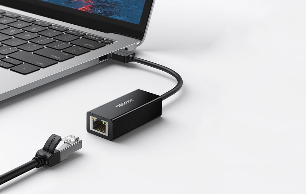 UGREEN USB-Ethernet adapter connected to a laptop, next to a black network cable with an RJ45 plug
