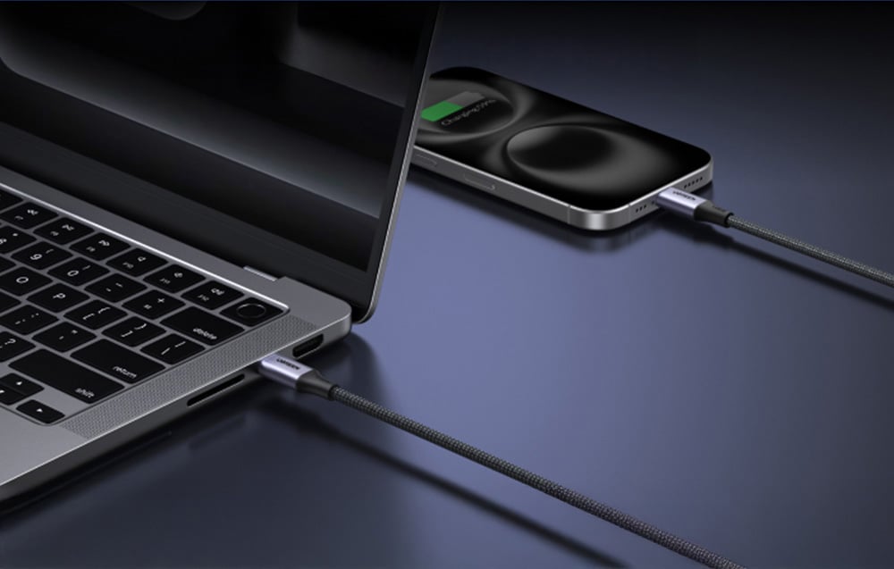 Laptop und Smartphone werden mit einem Doppelkabel auf dunklem Hintergrund geladen