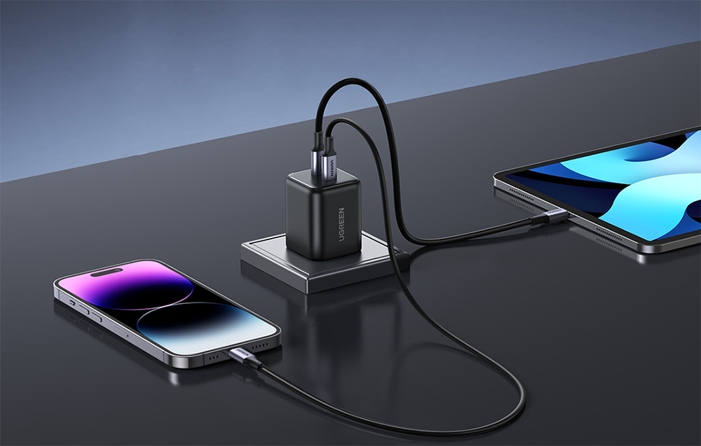 UGREEN charger charging both an iPhone and an iPad, devices lying on a gray countertop