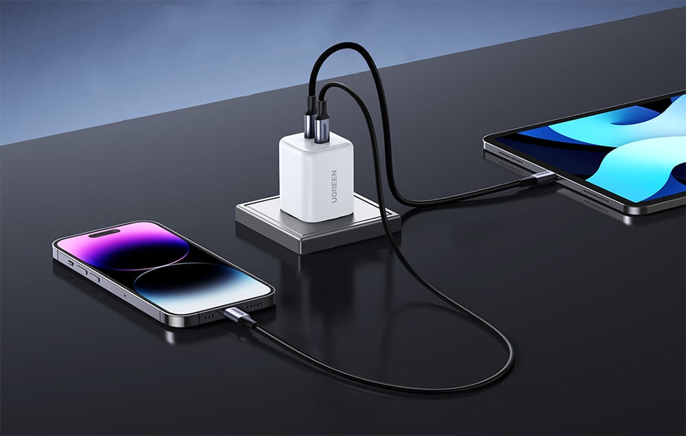 UGREEN charger charging both an iPhone and an iPad, devices resting on a gray countertop