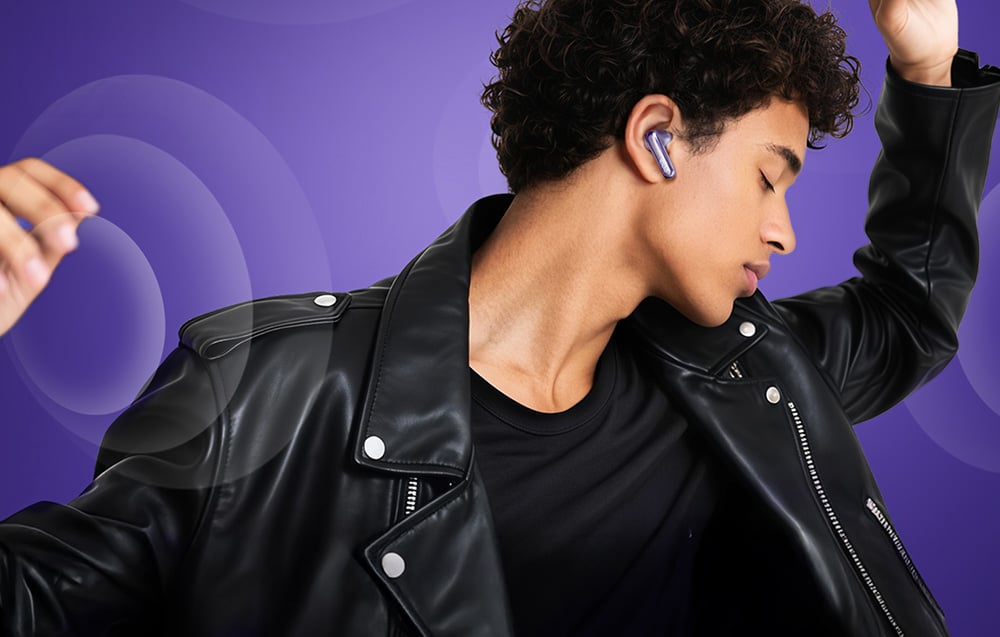 Mężczyzna w czarnej skórzanej kurtce z zamkniętymi oczami tańczy, mając w uchu bezprzewodową słuchawkę
