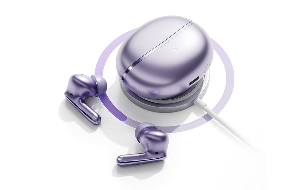Fioletowe słuchawki bezprzewodowe i etui ładujące umieszczone na okrągłej bezprzewodowej ładowarce