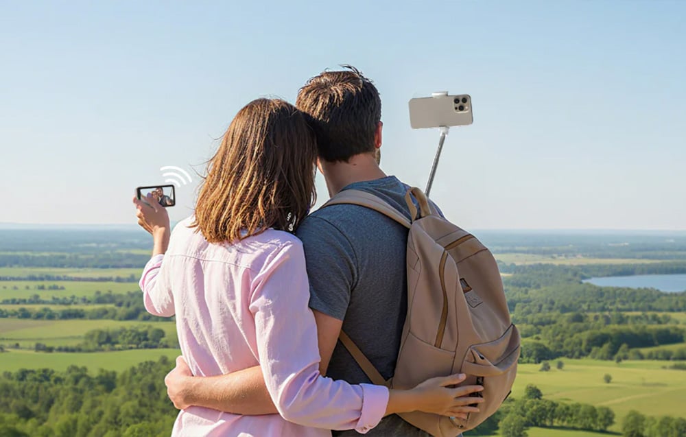 Para robi selfie smartfonem na wysięgniku na tle krajobrazu