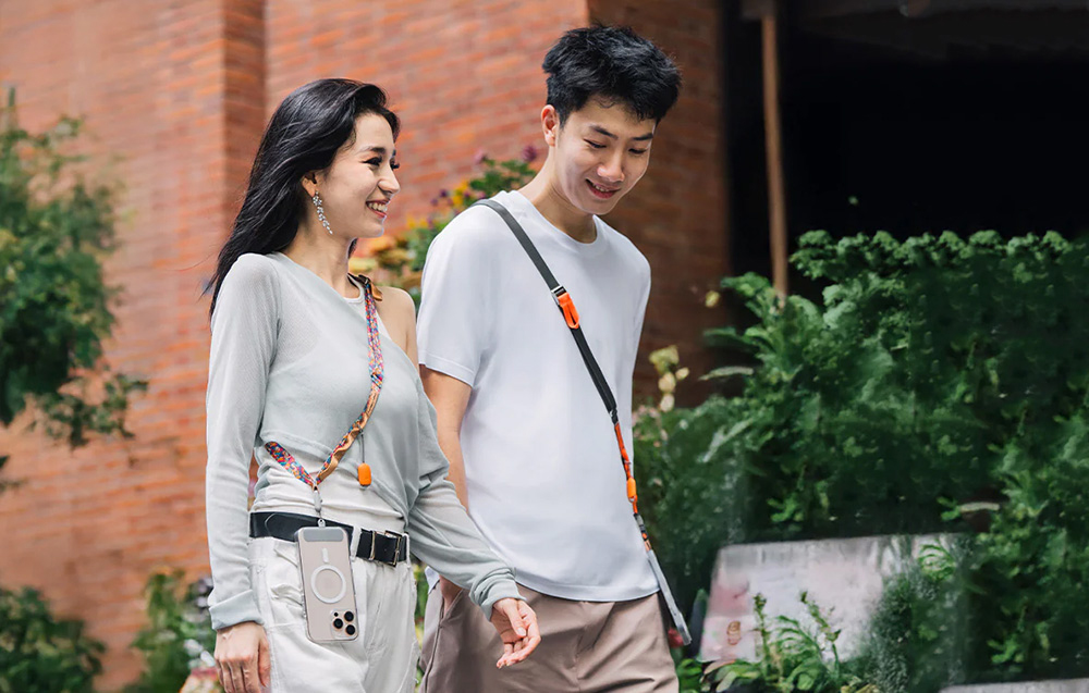 A woman and a man walking through the city with PGYTECH straps hanging from their shoulders