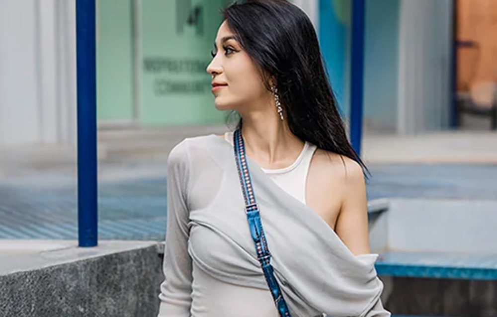 A woman with black hair wearing the PGYTECH strap slung over her shoulder