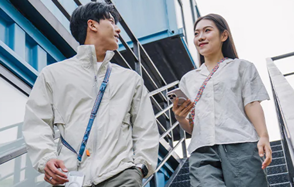 A woman and a man descending stairs, wearing PGYTECH straps slung over their shoulders