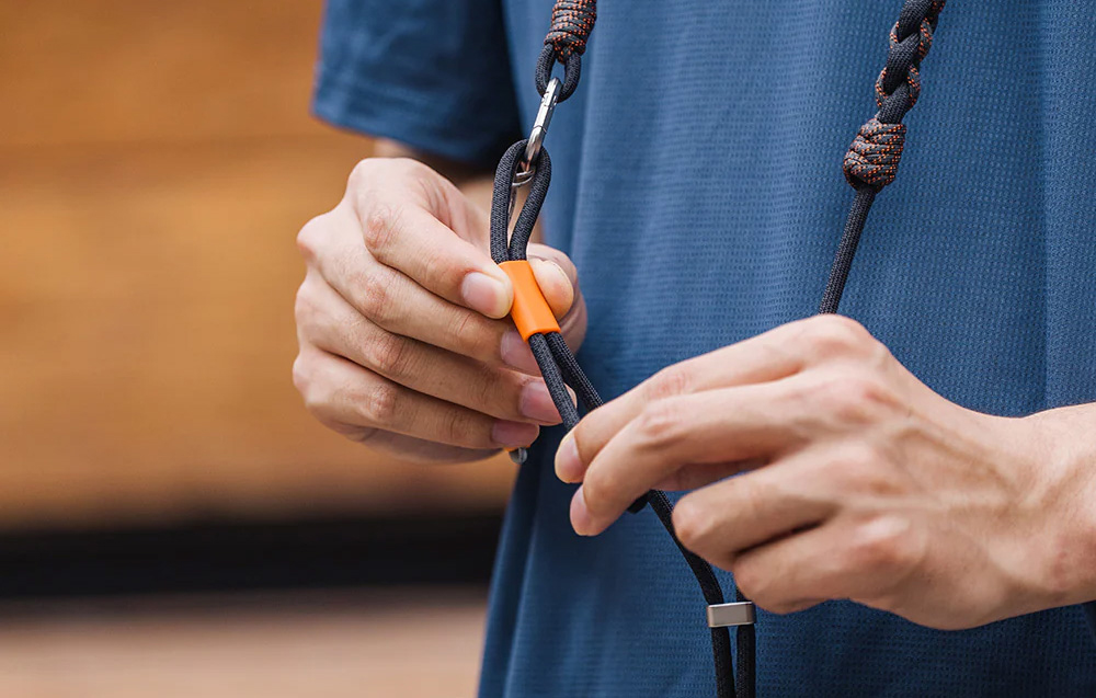 A man adjusting the black PGYTECH strap hanging around his neck