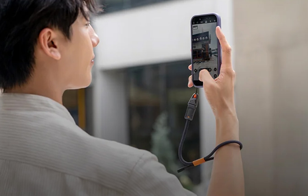 A man photographing a building with his smartphone attached to the PGYTECH strap