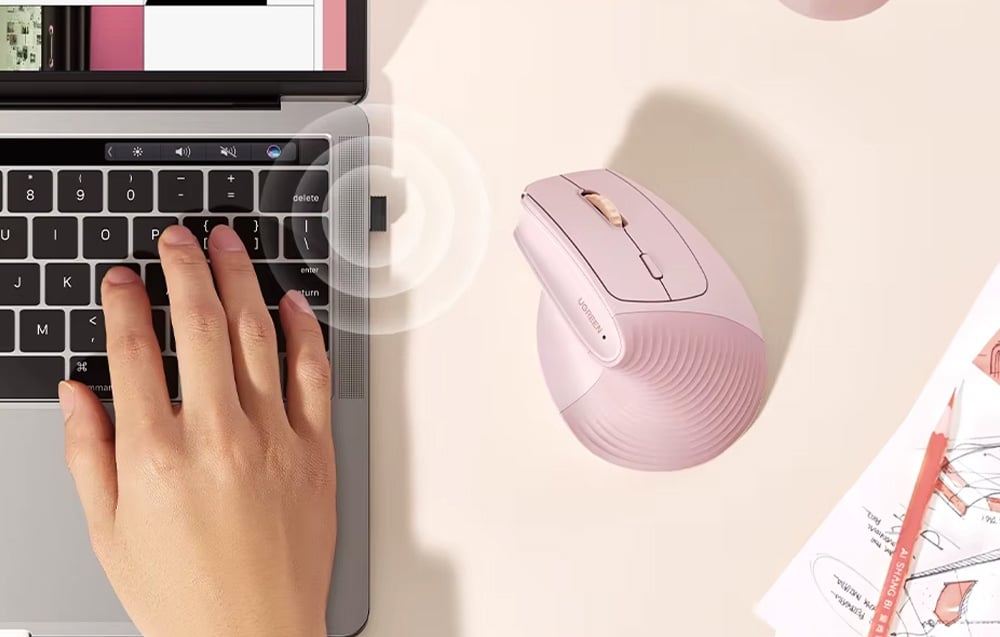 Różowa mysz pionowa Ugreen na biurku obok laptopa