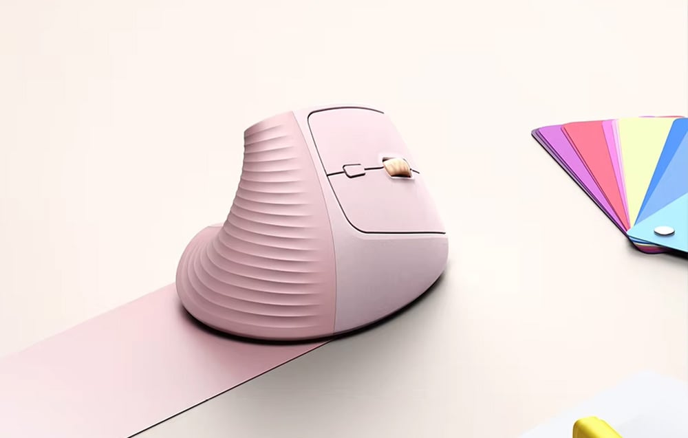 Różowa mysz pionowa na jasnym biurku obok kolorowych kartek