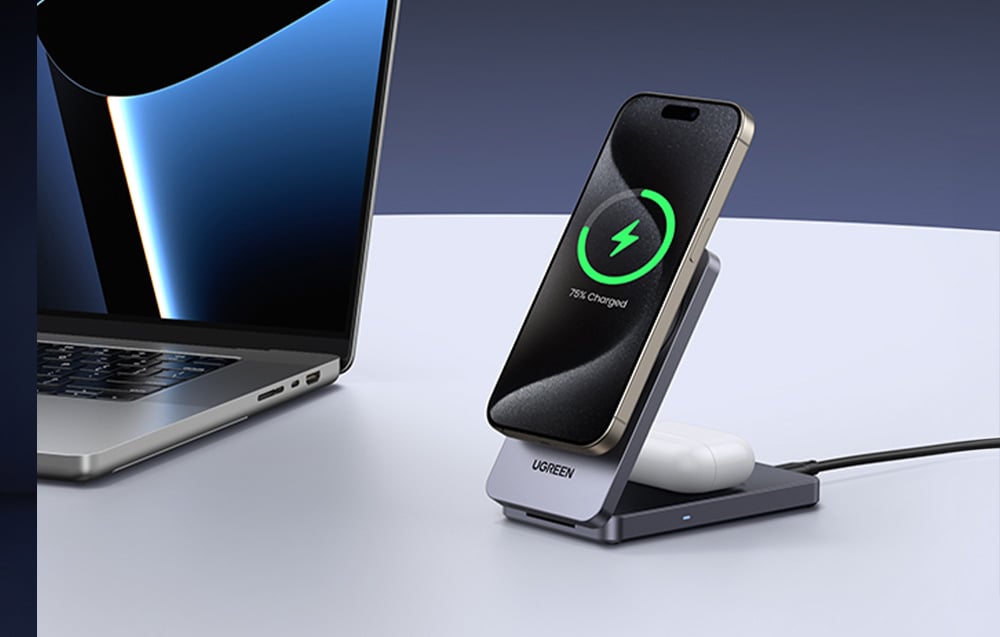 Smartfon i słuchawki TWS podłączone do ładowarki Ugreen. Obok laptop na biurku