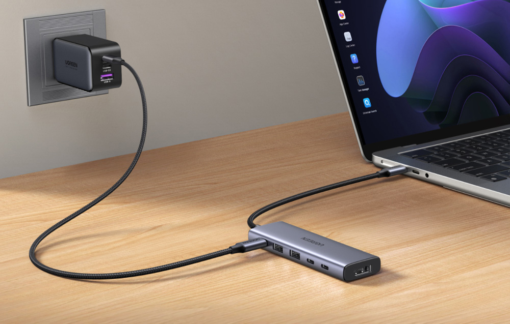 Hub Ugreen leży na biurku podłączony do ładowarki sieciowej i laptopa