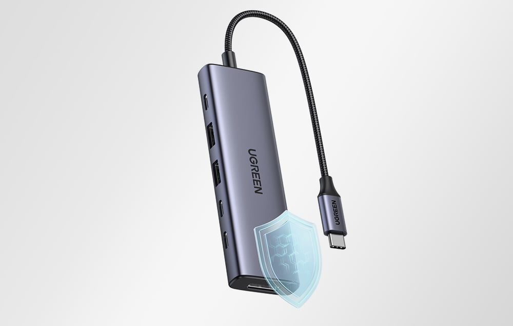 Szary hub Ugreen na jasnym tle, obok niego niebieska tarcza