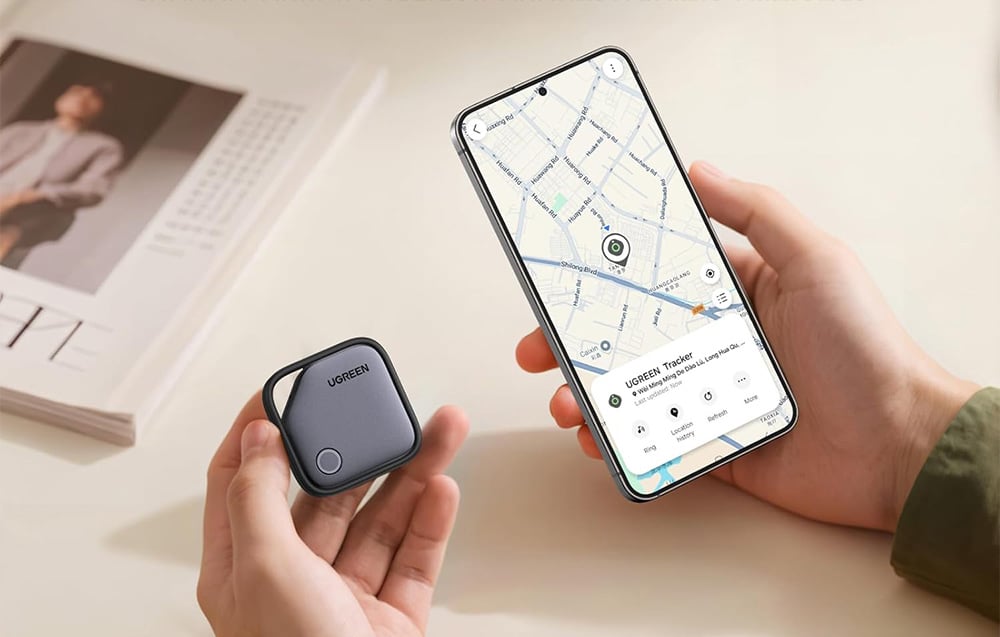 Trzymany w dłoni lokalizator Ugreen i smartfon z włączoną mapą