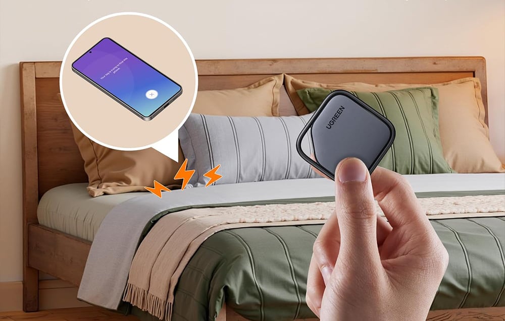 Trzymany w dłoni lokalizator na tle sypialni, na łóżku leży zgubiony telefon