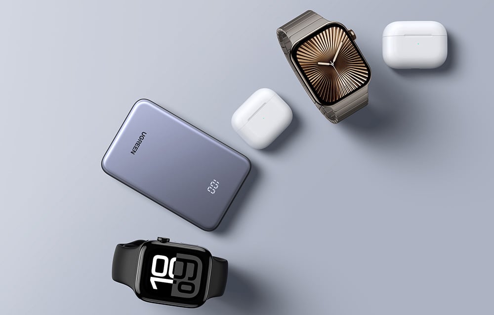 Ugreen-Powerbank neben Smartwatches und TWS-Kopfhörern auf grauem Hintergrund