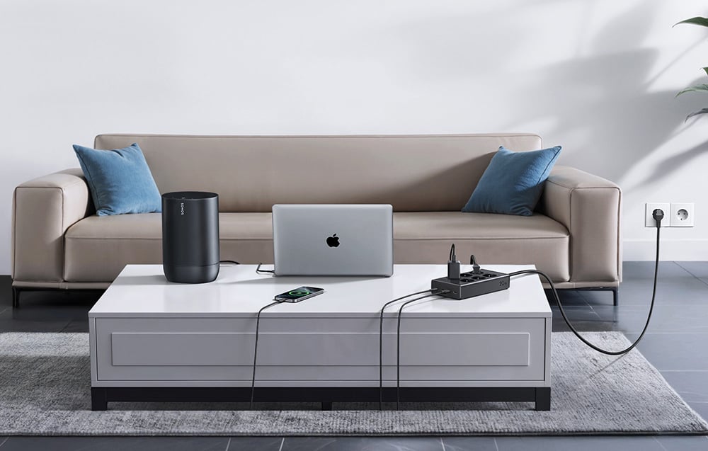 Several devices connected to the power strip on a white table in the living room