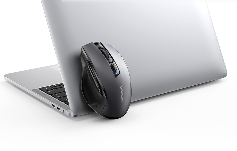 Czarna mysz bezprzewodowa Ugrene oparta o laptopa na białym tle