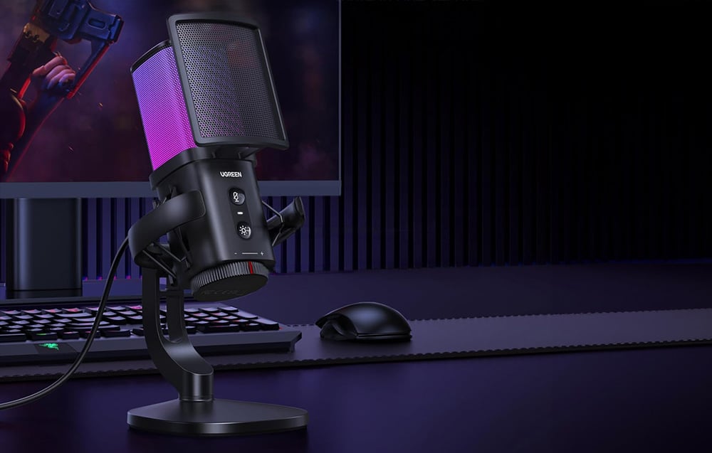 Czarny mikrofon Ugreen z kolorowym podświetleniem na biurku w ciemnym pokoju