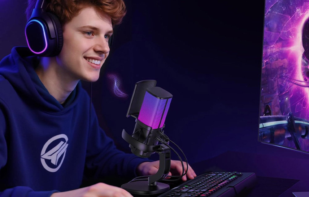 Uśmiechnięty chłopak siedzący przed biurkiem w słuchawkach, obok mikrofon