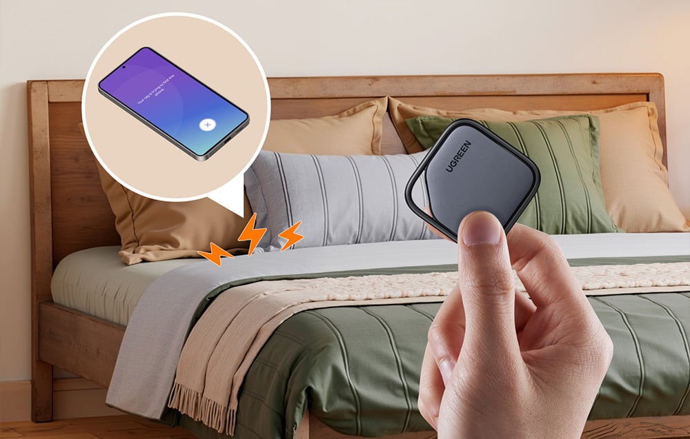 Der Locator wird in der Hand gehalten, im Hintergrund ein Smartphone auf dem Bett