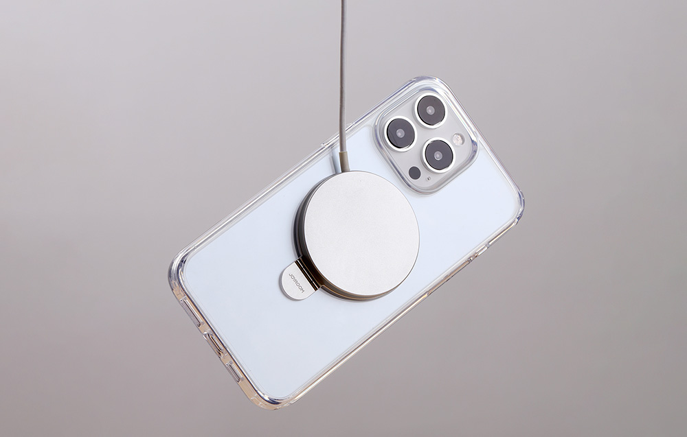 Smartfon z przezroczystym etui z magnetycznym elementem, podłączony kablem.