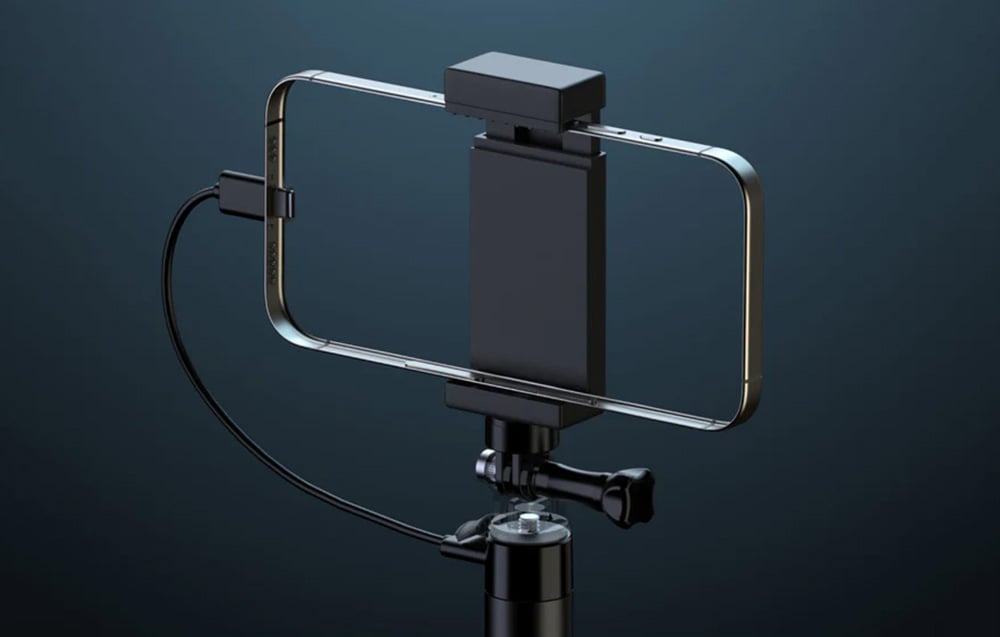 Smartfon przymocowany do selfie sticka i podłączony do ładowania 