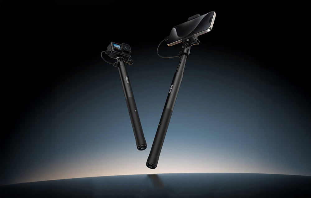 Smartfon i kamera przymocowane do selfie sticka na ciemnym tle