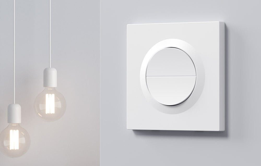 Biały okrągły przełącznik dotykowy SONOFF z dwoma przyciskami na tle minimalistycznych lamp wiszących