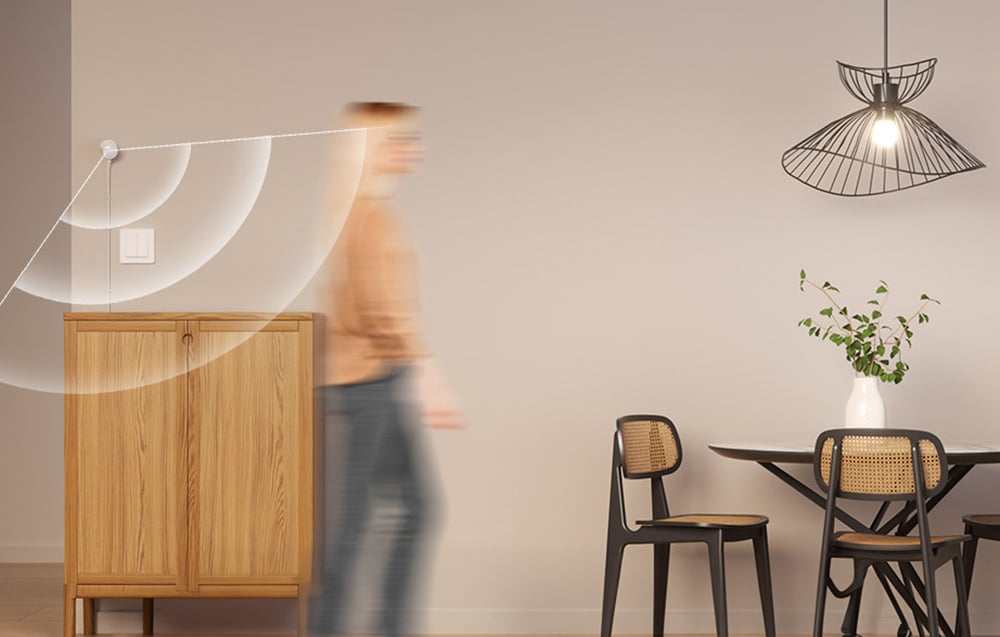 Osoba przechodząca przez nowoczesne wnętrze z drewnianą komodą, krzesłami rattanowymi i designerskimi lampami wiszącymi, z graficznym nałożeniem ilustrującym zasięg sygnału