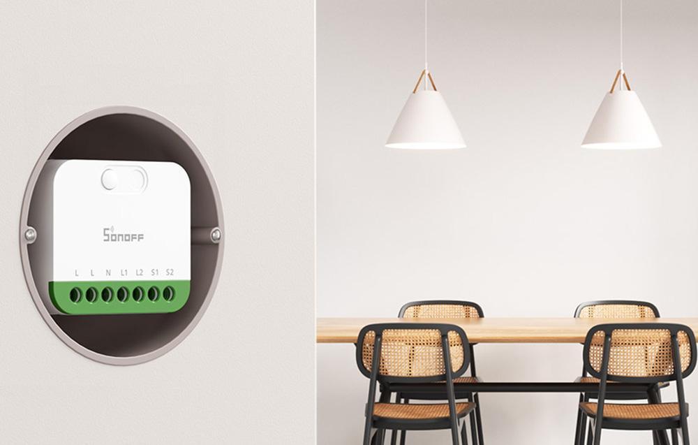 Kompaktowy przełącznik Sonoff zainstalowany w okrągłej puszce podtynkowej na białej ścianie, w jadalni z dwiema lampami wiszącymi i krzesłami z rattanowymi oparciami