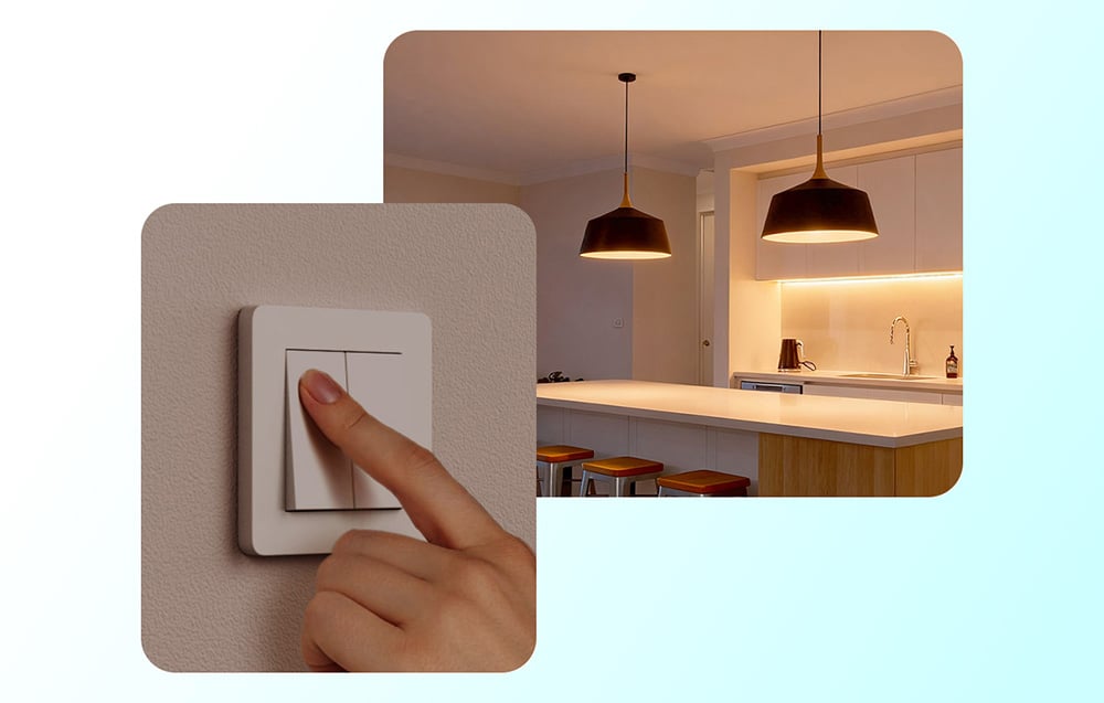 Dłoń naciskająca biały włącznik światła na ścianie, z widokiem nowoczesnej kuchni oświetlonej lampami wiszącymi w tle