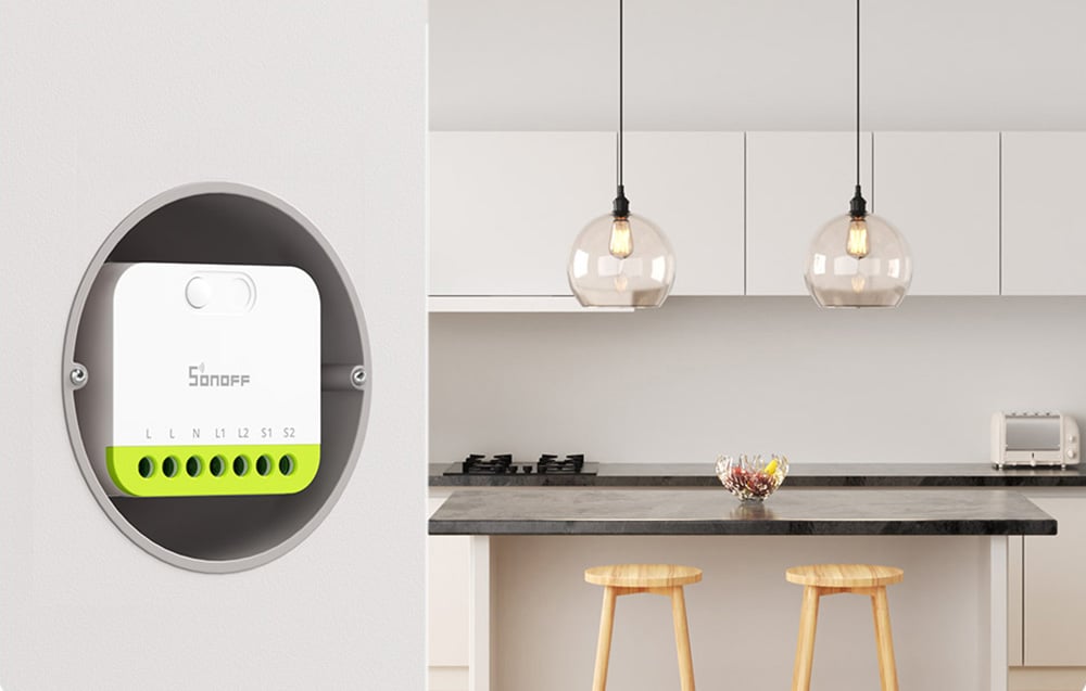 Inteligentny przełącznik Sonoff zamontowany w puszce ściennej obok nowoczesnej kuchni z dwoma wiszącymi lampami