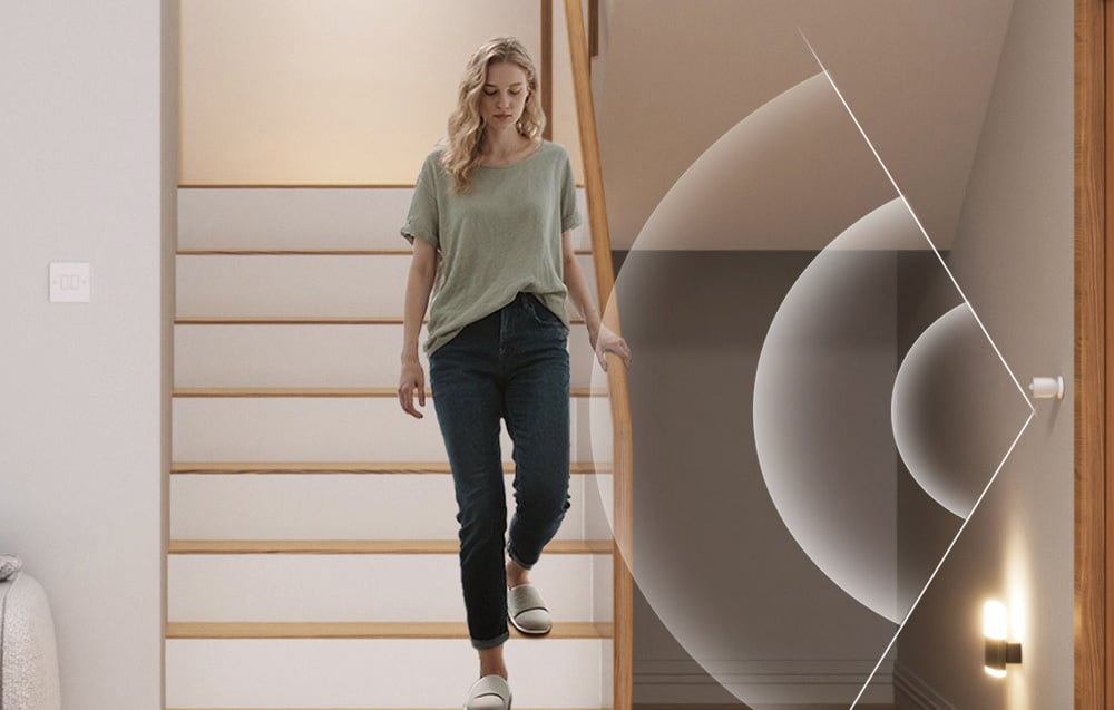 Kobieta schodzi po schodach w domu, obok wizualizacja działania czujnika ruchu