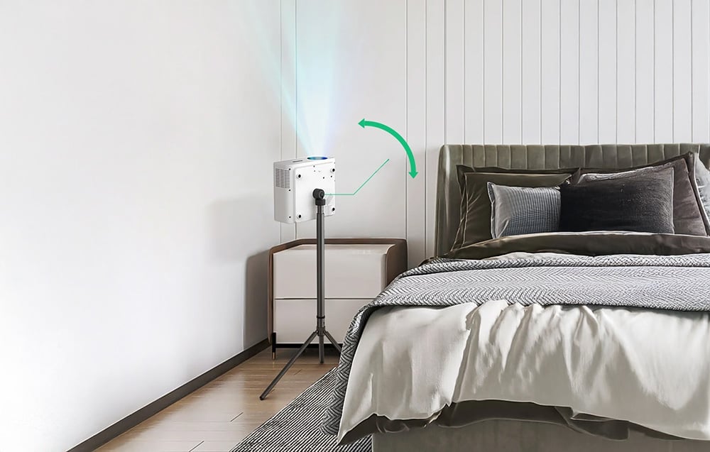 Projektor na statywie ustawiony obok łóżka, skierowany w stronę sufitu w nowoczesnej sypialni.