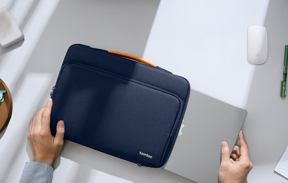 A man placing a laptop into a navy Tomtoc bag