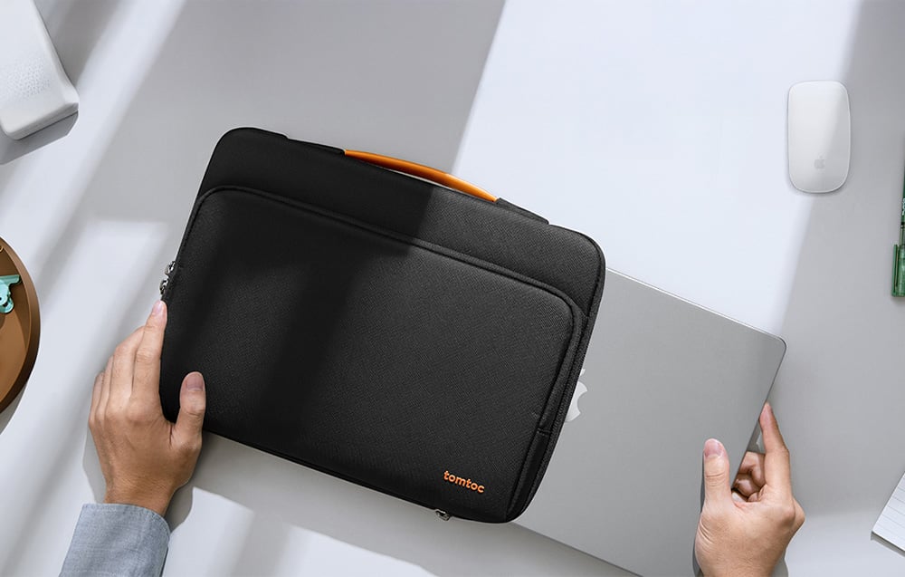 A man putting a laptop into a black Tomtoc bag