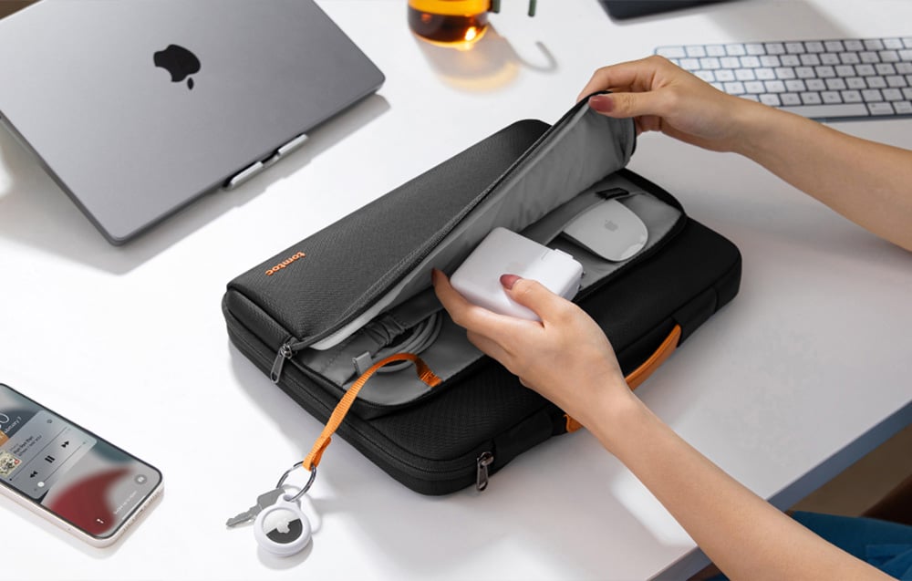 A woman putting a power adapter into a black laptop bag