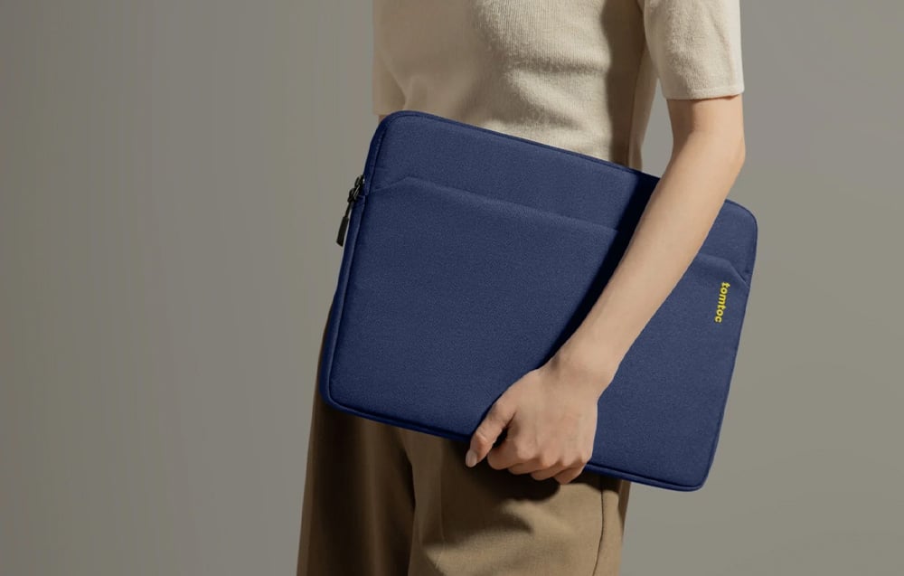 A woman in light clothing holding a navy tomtoc laptop bag