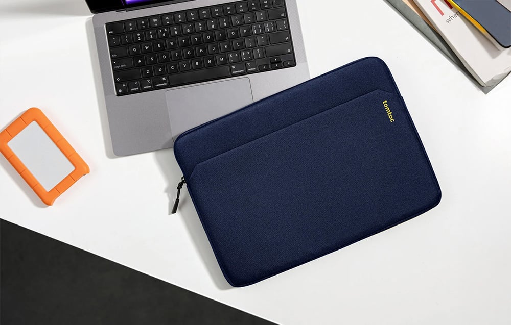 Navy tomtoc laptop bag next to a laptop on a desk