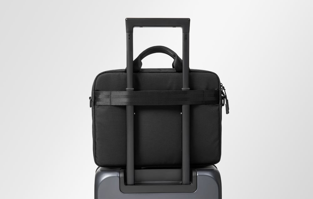 Czarna torba na laptopa przewieszona przez uchwyt walizki
