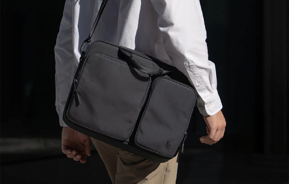 Mężczyzna w białej koszuli i jasnych spodniach z czarną torbą na ramieniu