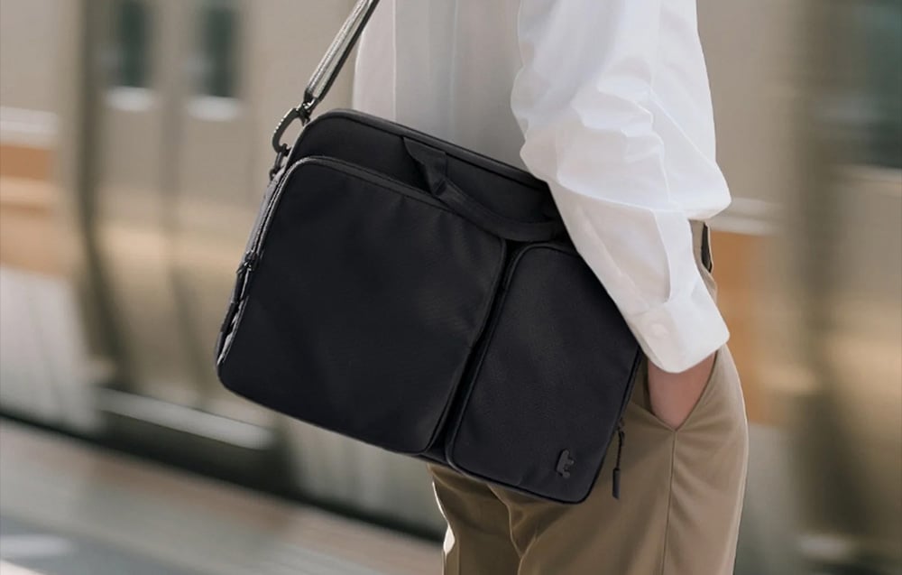 Mężczyzna w białej koszuli z czarną torbą na ramieniu na dworcu