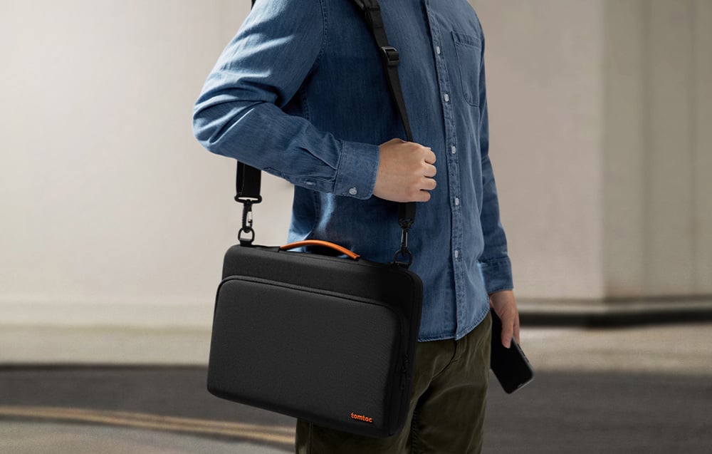 Person in a denim shirt with a black shoulder bag and a smartphone in hand