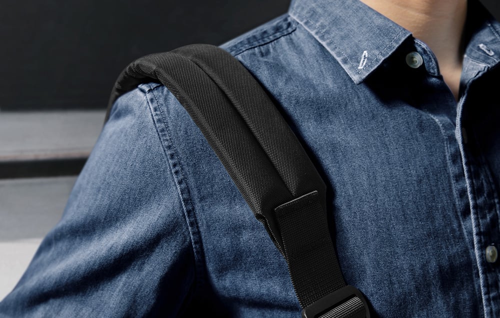 Close-up of the bag's strap worn over the shoulder of a person in a denim shirt