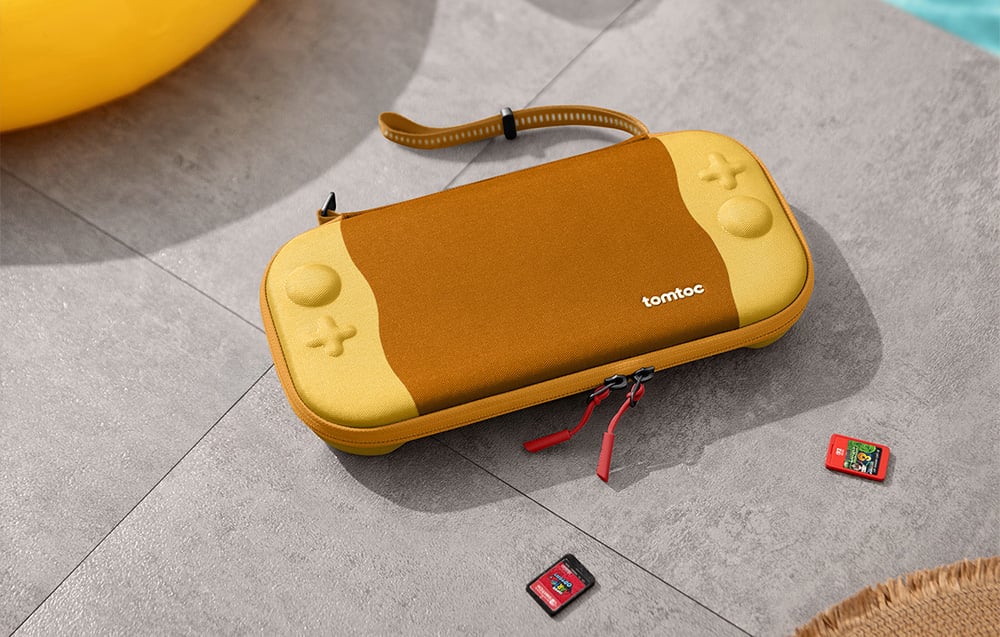 Żólte etui na konsolę Nintendo Switch na szarych kafelkach obok kart