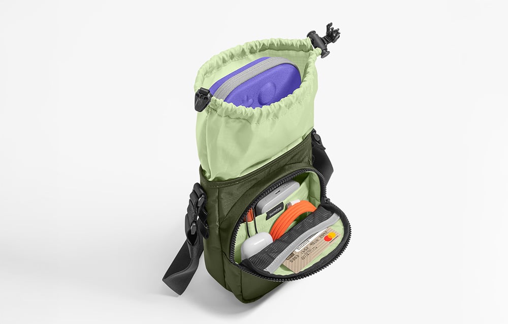 A green bag packed with a console, power bank, and other accessories