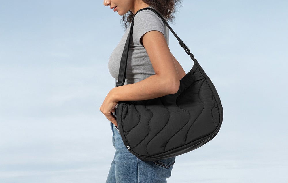 Kobieta w szarej koszulce z czarną torebką na ramieniu