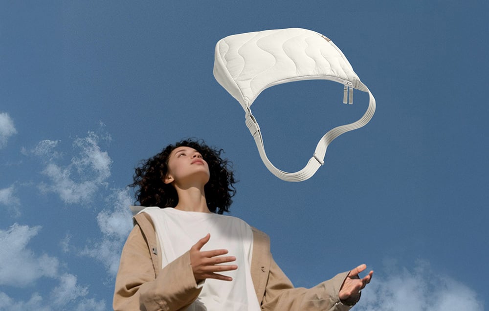 Frau, die eine weiße Tasche in die Höhe wirft, im Hintergrund blauer Himmel